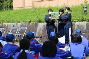 青空の下で紙芝居読み聞かせの様子